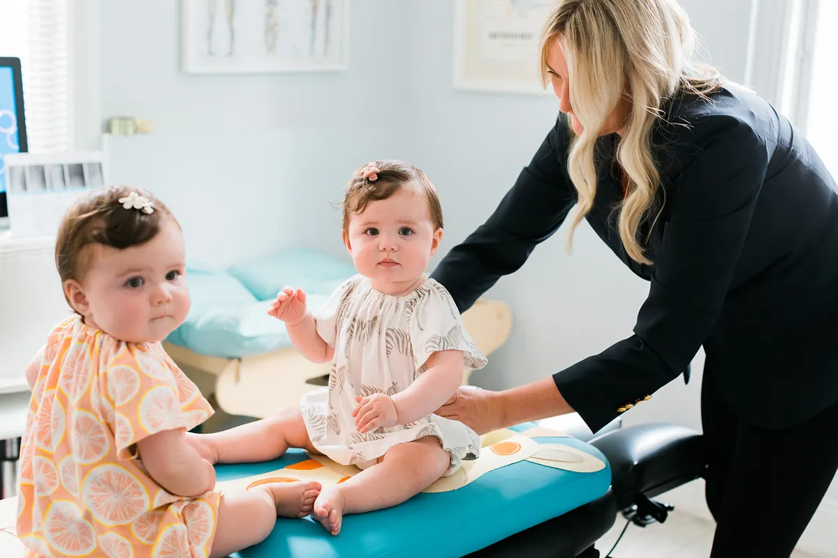 Two infants sitting on the pediatric adjusting table